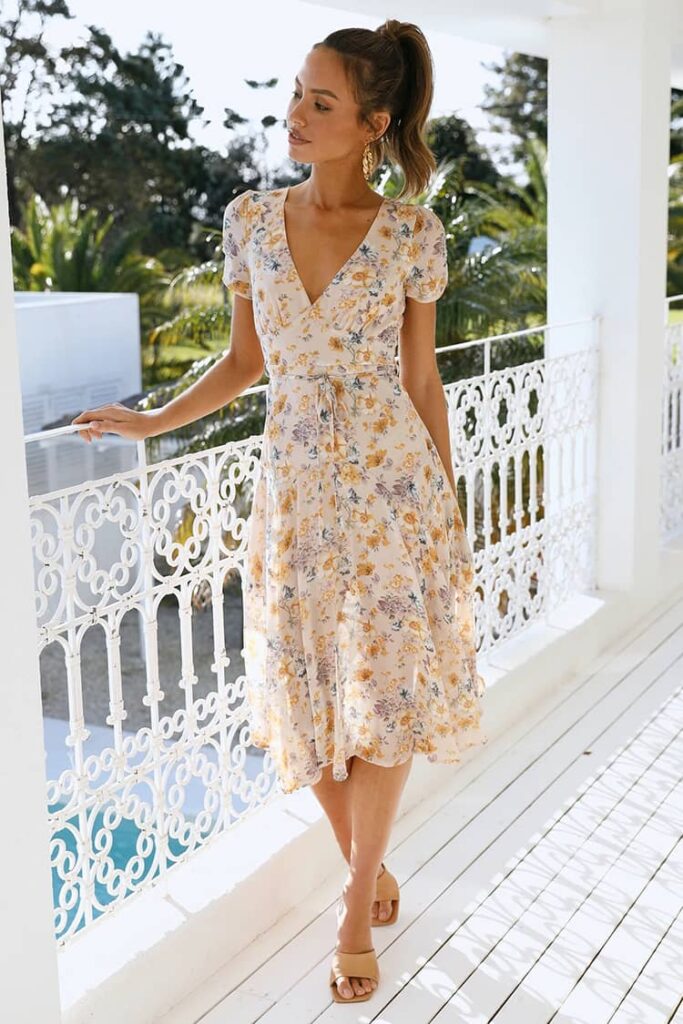 Woman in a white sequin gown with a deep V-neck, the perfect wedding guest dress for an evening or formal wedding.