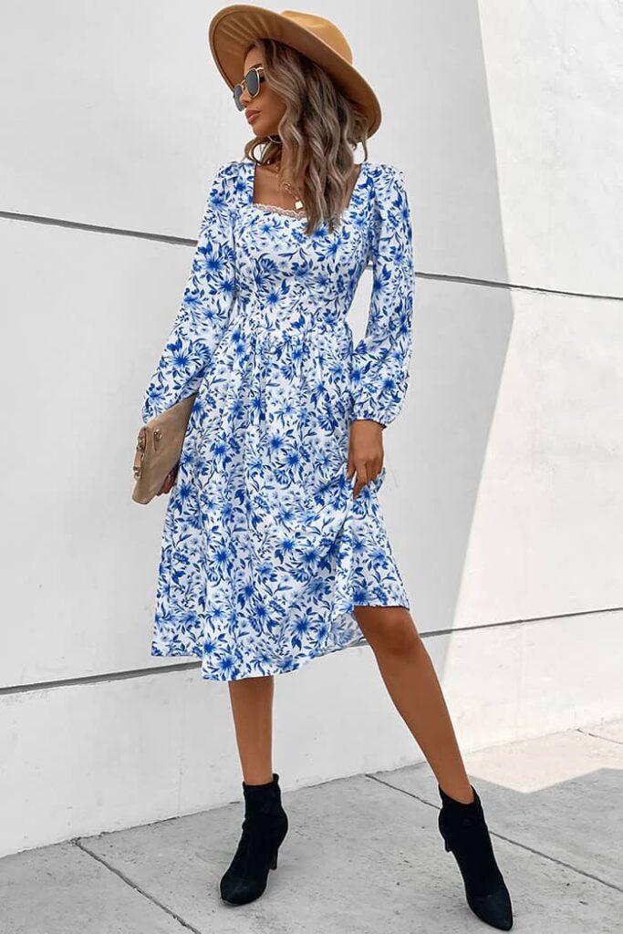 A woman in a blue and white floral-print midi dress paired with sunglasses and a wide-brimmed hat, one of the best dresses to beat the heat on sunny days.