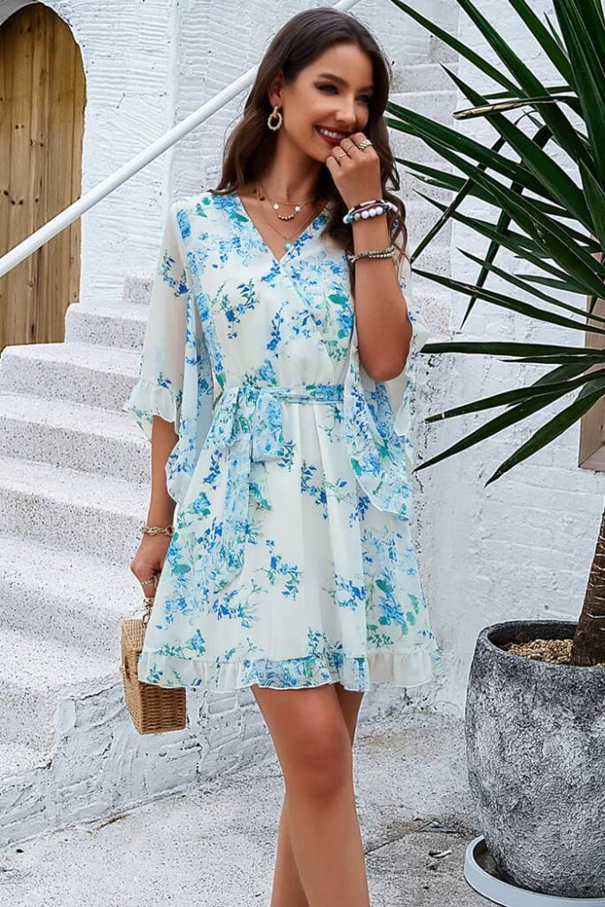 A flowy white and blue wrap dress with floral patterns, designed to be one of the best dresses to beat the heat at summer events.